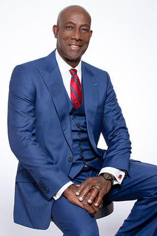 Dr. Keith Christopher Rowley wearing a blue suit, white shirt, and red tie.