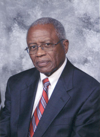 Fred D. Gray, Esquire wearing a navy blue blazer, white dress shirt, glasses and a red, white and blue tie.