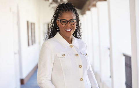 Photo of Thasunda-Duckett wearing glasses and a white blazer with gold buttons.