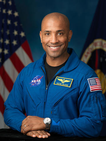 Photo of Victor Glover, Jr. wearing his blue Nasa uniform that with the NASA Logo and American Flag patches.