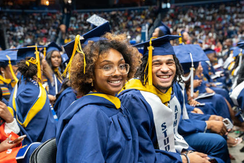Male and female graduates smiling and wearing their Howard Regalia.